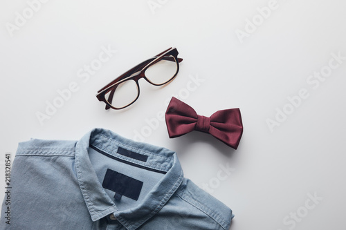 top view of blue shirt, burgundy bow tie and glasses isolated on white