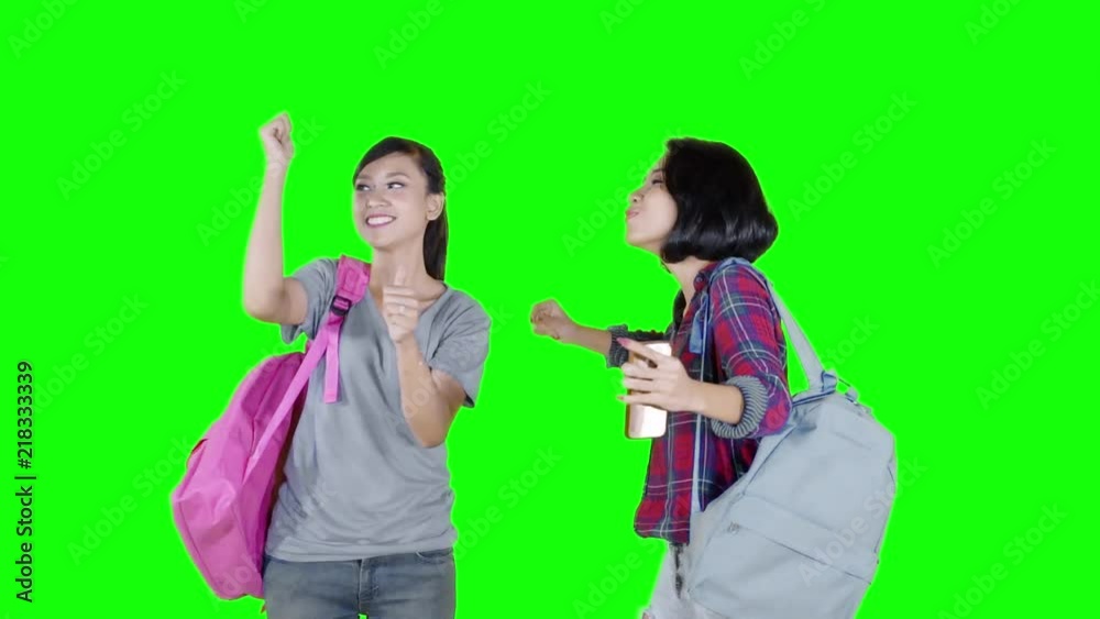 Two female high school student celebrating their success by dancing together in the studio with green screen background Two female high school student celebrating their success by dancing together in the studio with green screen background