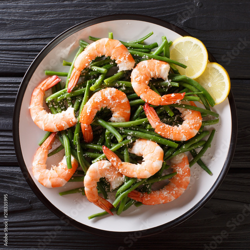 Delicious shrimp salad with green beans, cheese and lemon close-up on a plate. top view from above