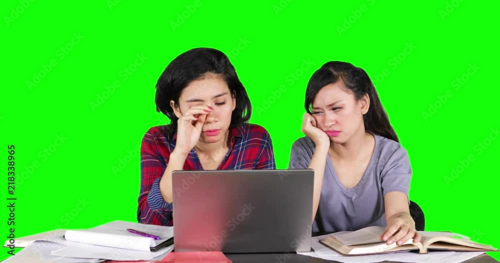 Two female students looks sleepy while studying together with a laptop computer. Shot in 4k resolution with green screen background Two female students looks sleepy while studying together with a laptop computer. Shot in 4k resolution with green screen background