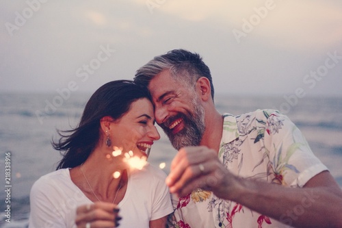 Canvas Print Couple celebrating with sparklers at the beach