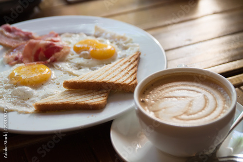 breakfast with fried eggs, bacon, toasts and cappuccino