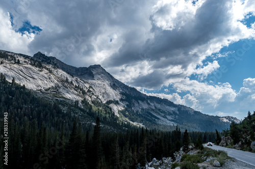 Road trip through the Tioga pass in Yosemite National Park, California USA. Dramatic sky and clouds over the epic mountains and forest. 