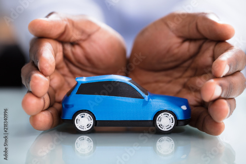 Businessman's Hand Protecting Blue Toy Car