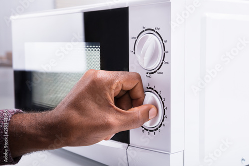Man Adjusting Temperature Of Microwave Oven