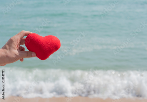 Hand with heart red shape and sea .