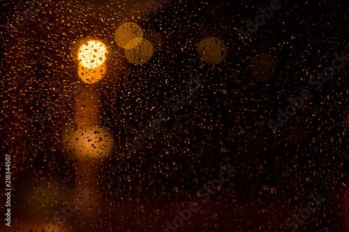 Rain drops on the window. Rain drops on the glass on a background of a night blurred city. Rainy weather. Outside the window is a blurred city. Bokeh night city.