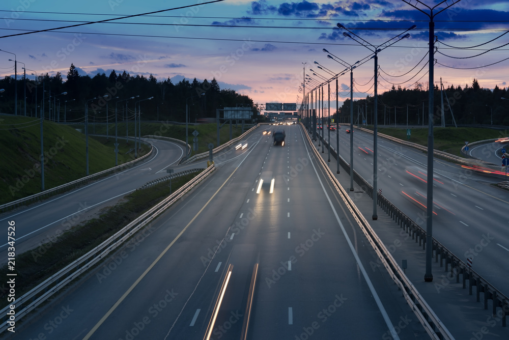 fast cars on highway in evening light. Road with metal safety barrier or rail. Sunset