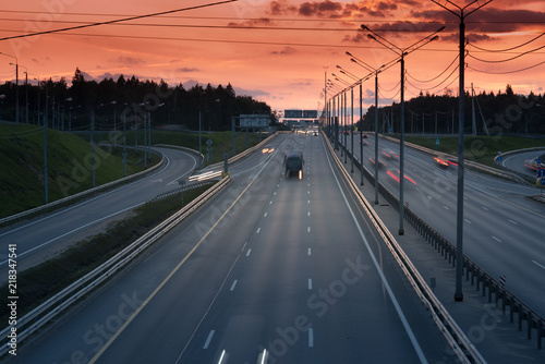 fast cars on highway in evening light. Road with metal safety barrier or rail. Sunset