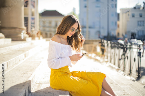 Beautiful girl with smartphone sitting on the stairs