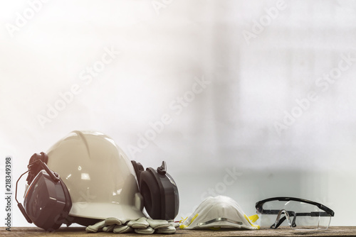 PPE onsist with White safety helmet (hard hat) with ear muff attached,Respiratory protection, Pair of leather gloves and transparent plastic glasses, Engineering and construction concept.
