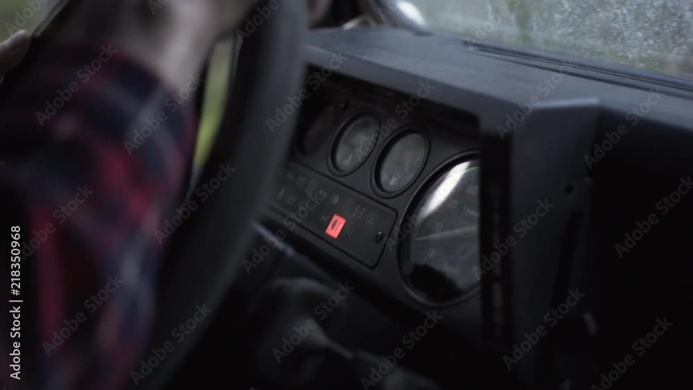 Outdoorsy man arms on the wheel driving a vintage 4x4, focus on instrument panel, handheld Outdoorsy man arms on the wheel driving a vintage 4x4, focus on instrument panel, handheld