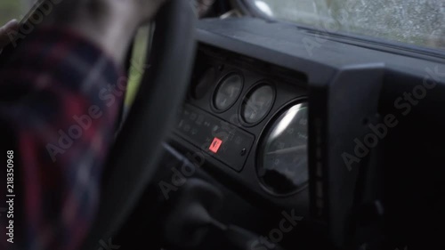 Outdoorsy man arms on the wheel driving a vintage 4x4, focus on instrument panel, handheld