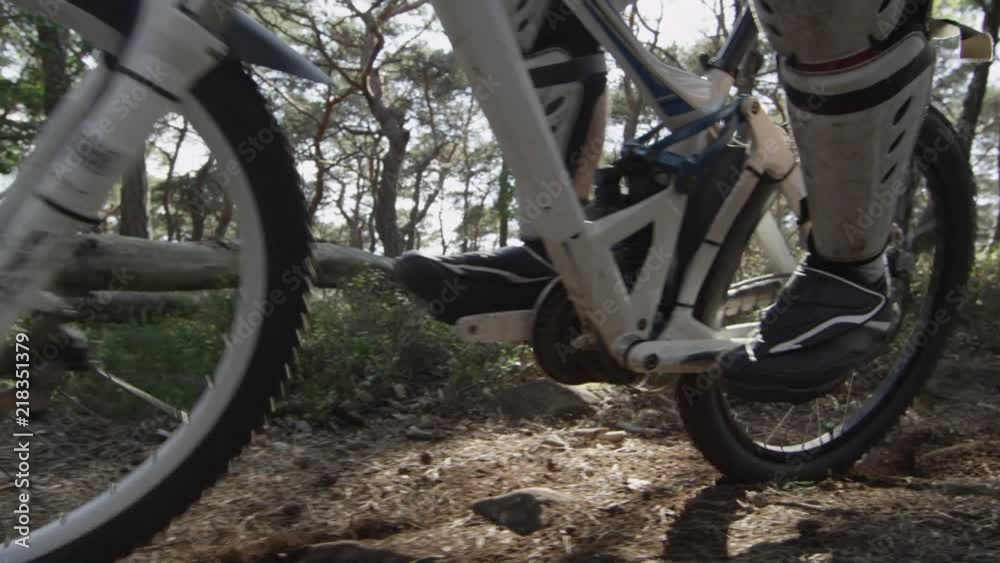 travelling hand-held shot of a downhill mountain biker on a dusty path in a forest travelling hand-held shot of a downhill mountain biker on a dusty path in a forest