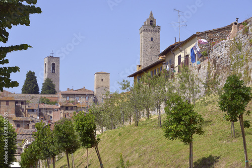 San Gimignano and the big stone towers, with trees in the foreground. Gimignano is a walled medieval hill town in the province of Siena, Tuscany, north-central Italy