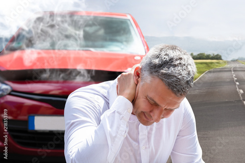 Man Suffering From Neck Pain In Front Of Breakdown Car