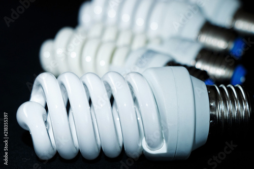 Electric white lightbulbs in the form of spirals on a black background.