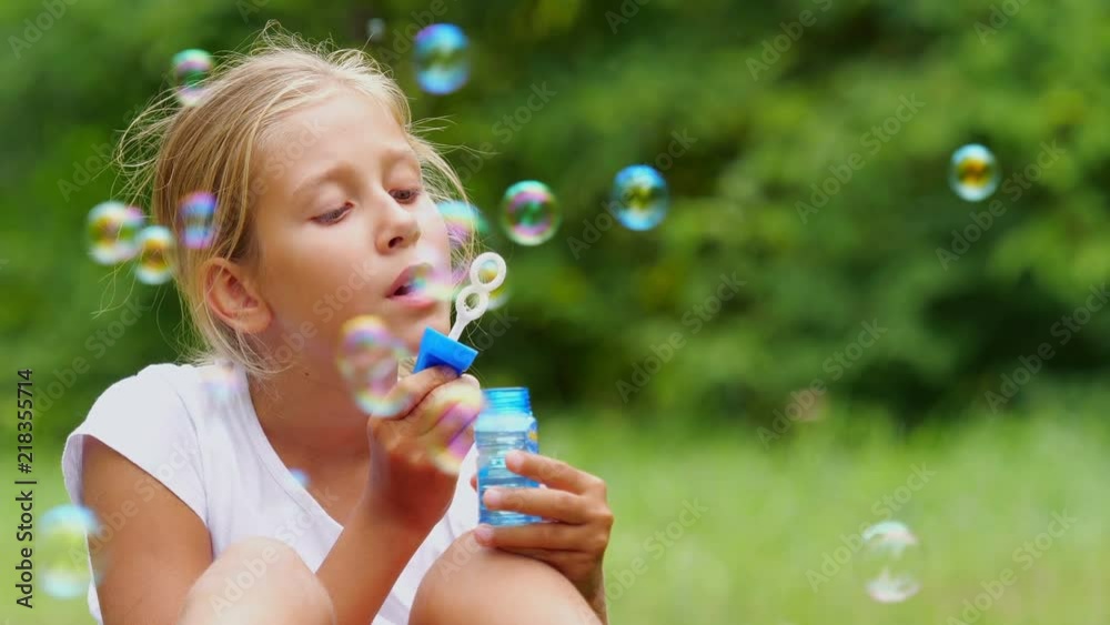 Little girl playing with soap bubbles outdoor. Slow motion. Little girl playing with soap bubbles outdoor. Slow motion.