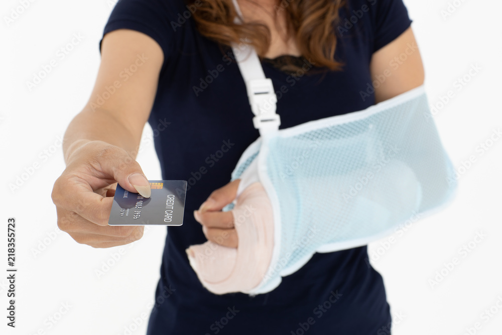 Arm broken beautiful Asian woman with arm sling showing and using credit card. Studio shot on white background. Concept for expense moneycost for health when accident happened. Focus on card