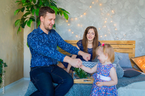 Happy young parents and their baby daughter playing togerher at home. Family, childhood and leisure concept photo