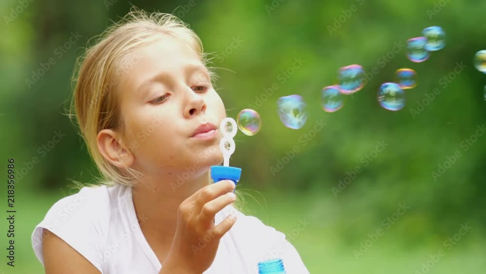 nine-year-old girl plays with soap bubbles in the summer garden.
nine-year-old girl plays with soap bubbles in the summer garden.