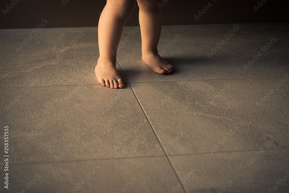 Barefoot baby are staying on heating tile floor.