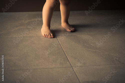 Obraz na płótnie Barefoot baby are staying on heating tile floor. w salonie
