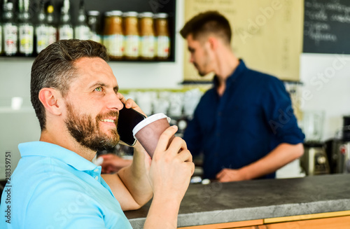 Happy to hear you. Man solving problems phone have coffee. Confident entrepreneur choose drink in paper cup to go while communicate mobile. Man speak mobile phone and drink coffee cafe bar background © be free