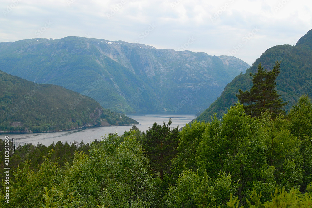 Summer landscape with mountains, forest and lake at the foreground in rural Norway.
