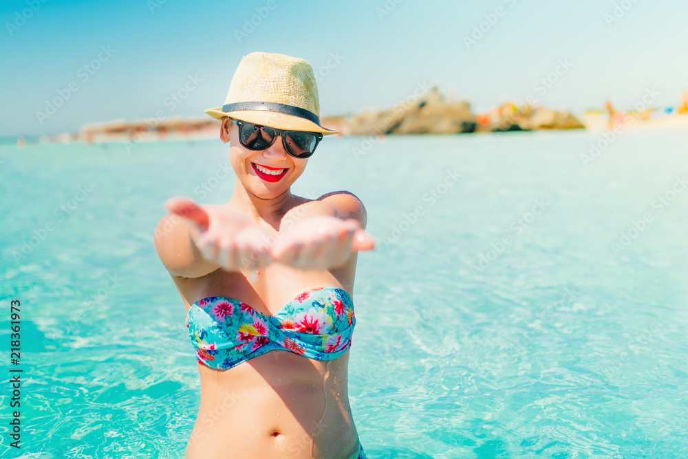 woman in swimsuit and straw hat smiling on tropical beach, enjoying sunny days and vacation
