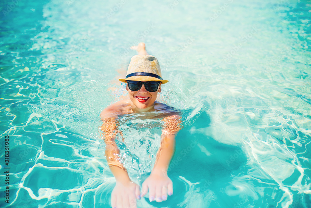 beautiful portrait of attractive woman sunbathing and smiling at camera. Summer beach holiday, pool details