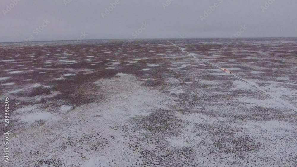 Aerial view of suvs moving through the snow-covered desert in winter. Western Kazakhstan, Mangyshlak Peninsula. Aerial view of suvs moving through the snow-covered desert in winter. Western Kazakhstan, Mangyshlak Peninsula.