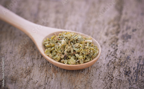 Oregano on wooden spoon isolated on wwooden background. photo