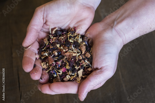 High angle close up of person holding small heap of red berry herbal tea infusion. photo