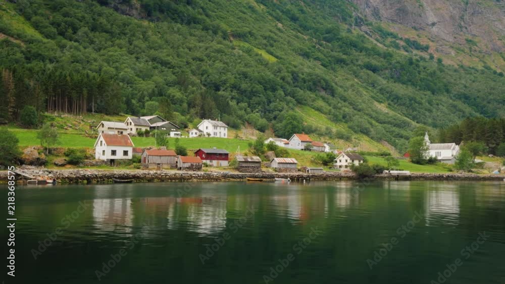A picturesque village with traditional wooden houses on the shore of the fjord in Norway. View from a floating cruise liner A picturesque village with traditional wooden houses on the shore of the fjord in Norway. View from a floating cruise liner
