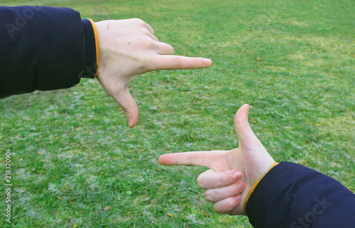 The frame from the hands framed by green grass, finger frame