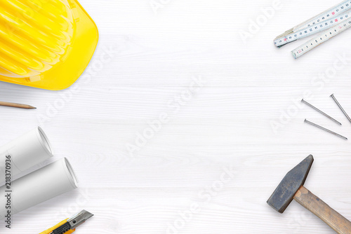 Builder helmet, tools and plans on white desk with free space fot text. Top view. photo