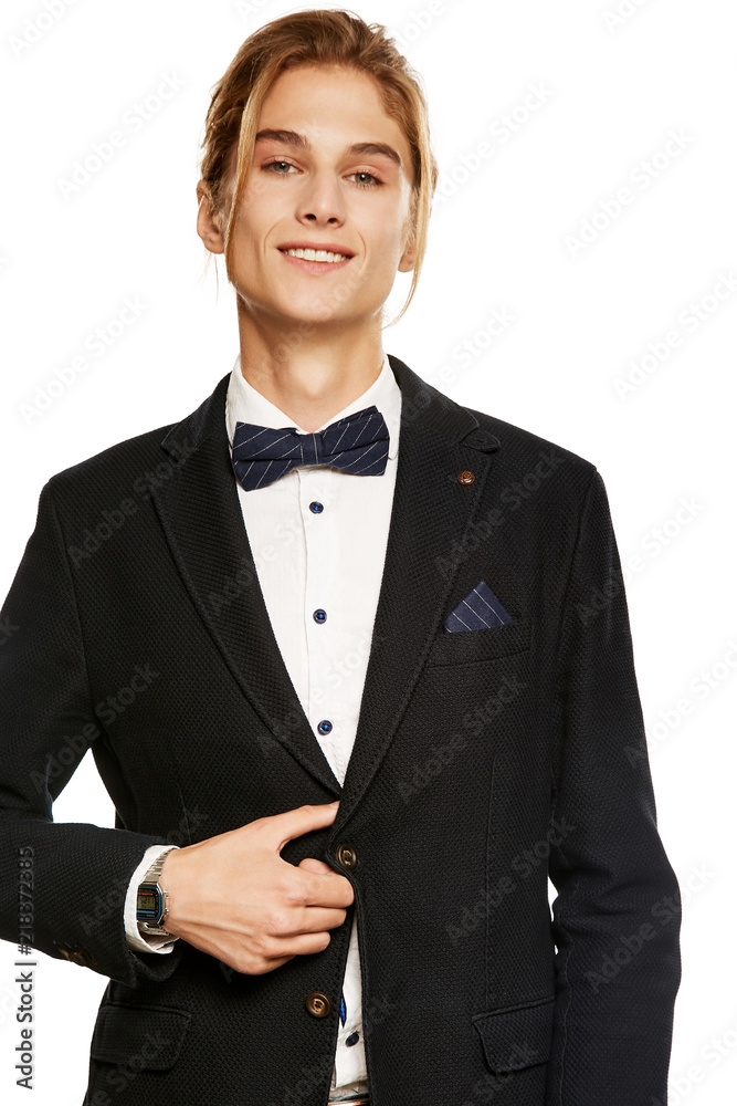 A handsome young man in a black suit jacket and shirt, accessorized with a  navy blue