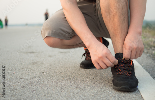 Man is tying shoes laces for jogging at park.