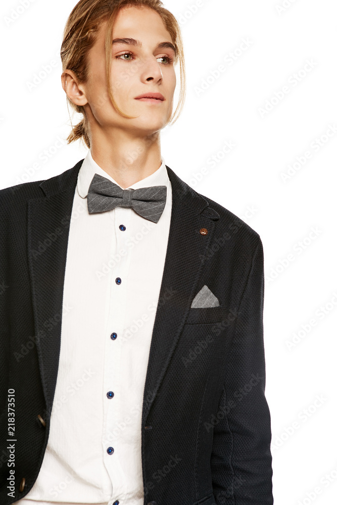 Foto Stock A Handsome Young Man In A Black Suit Jacket And Button Up Shirt,  Accessorized With A Grey Pinstripe Bow Tie And Pocket Square. The Blond Guy  With A Ponytail Looking
