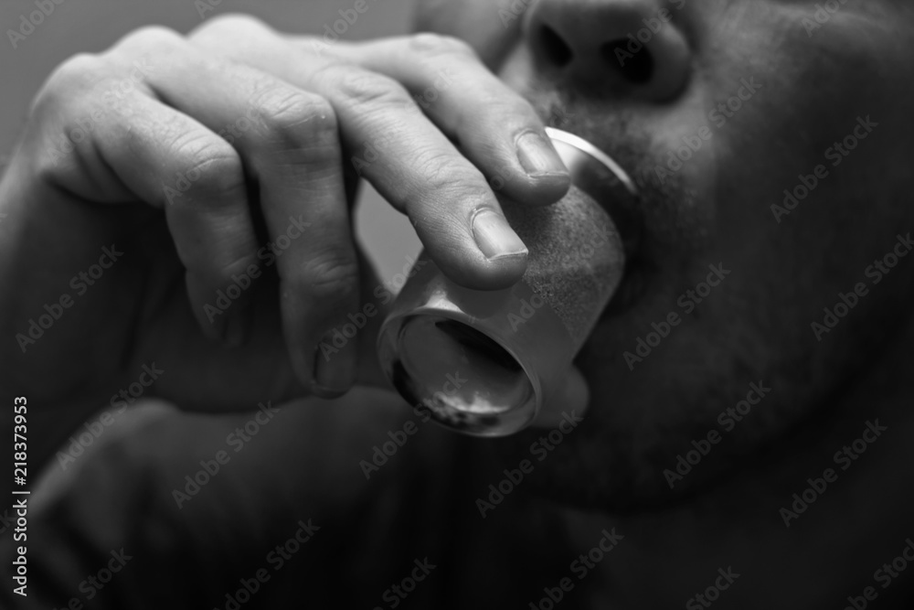 Fototapeta premium Drunk and unshaven male alcoholic finishes his vodka from the shot glass.