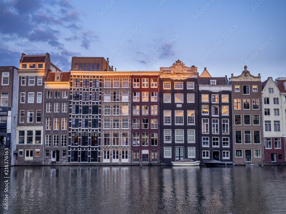 Historic buildings on the Damrak canal in the centre of beautiful Amsterdam at night.