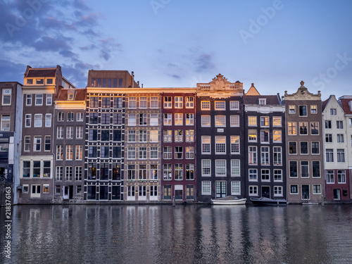 Historic buildings on the Damrak canal in the centre of beautiful Amsterdam at night.