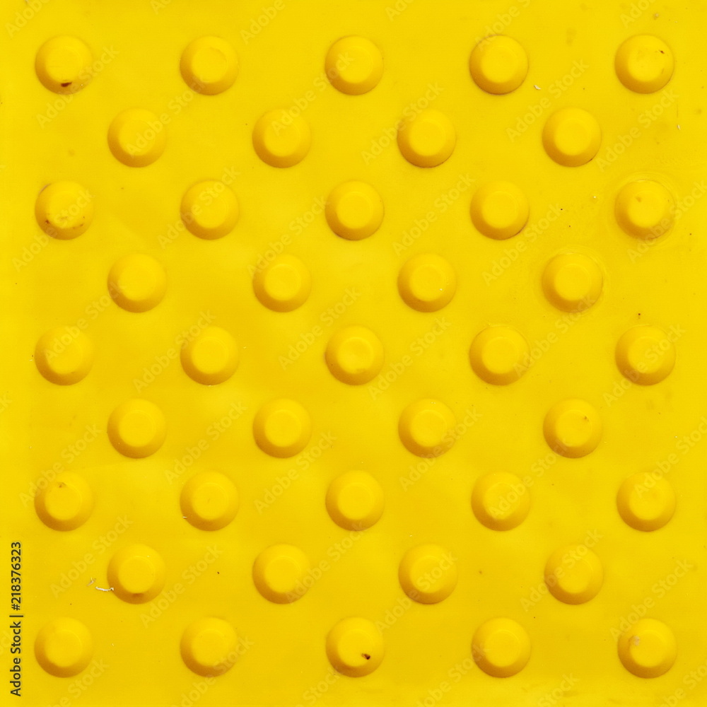 Top view of footpath tiles. Yellow circle buttons pattern. A stop signal for blind person. Solid square background