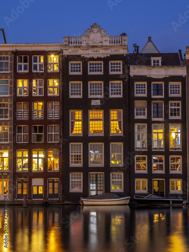 Historic buildings on the Damrak canal in the centre of beautiful Amsterdam at night.