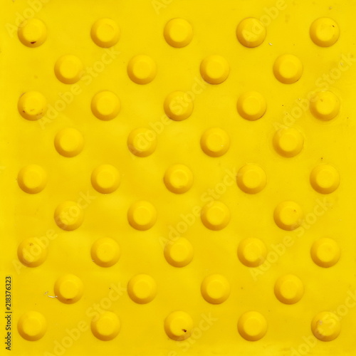 Top view of footpath tiles. Yellow circle buttons pattern. A stop signal for blind person. Solid square background