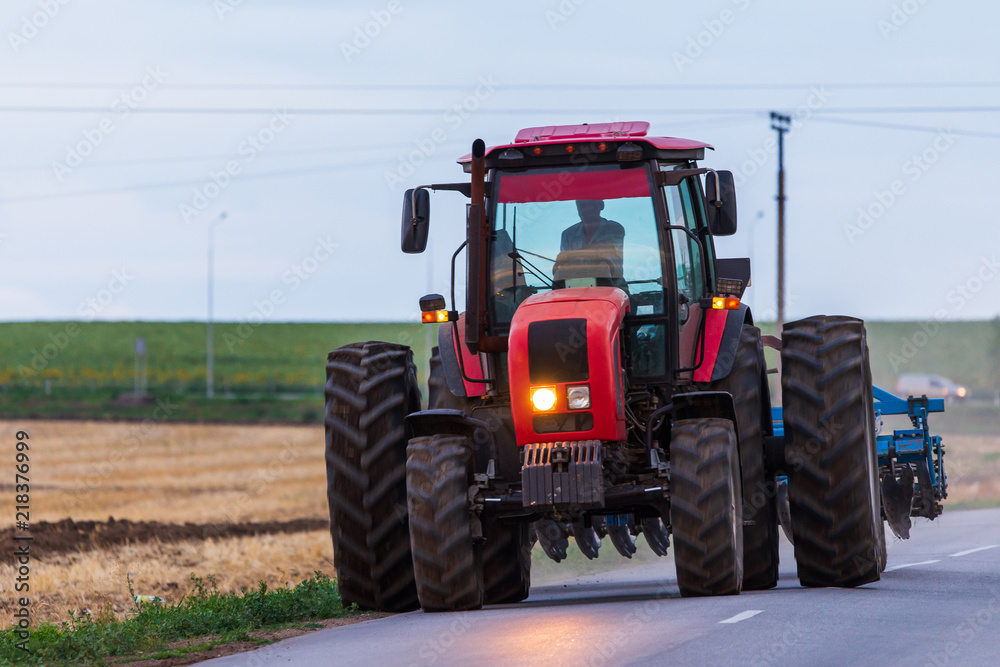 Agricultural tractor moving on the asphalt road after working in field