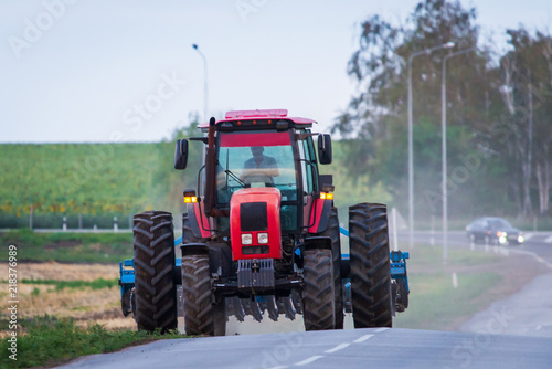 Agricultural tractor moving on the asphalt road after working in field