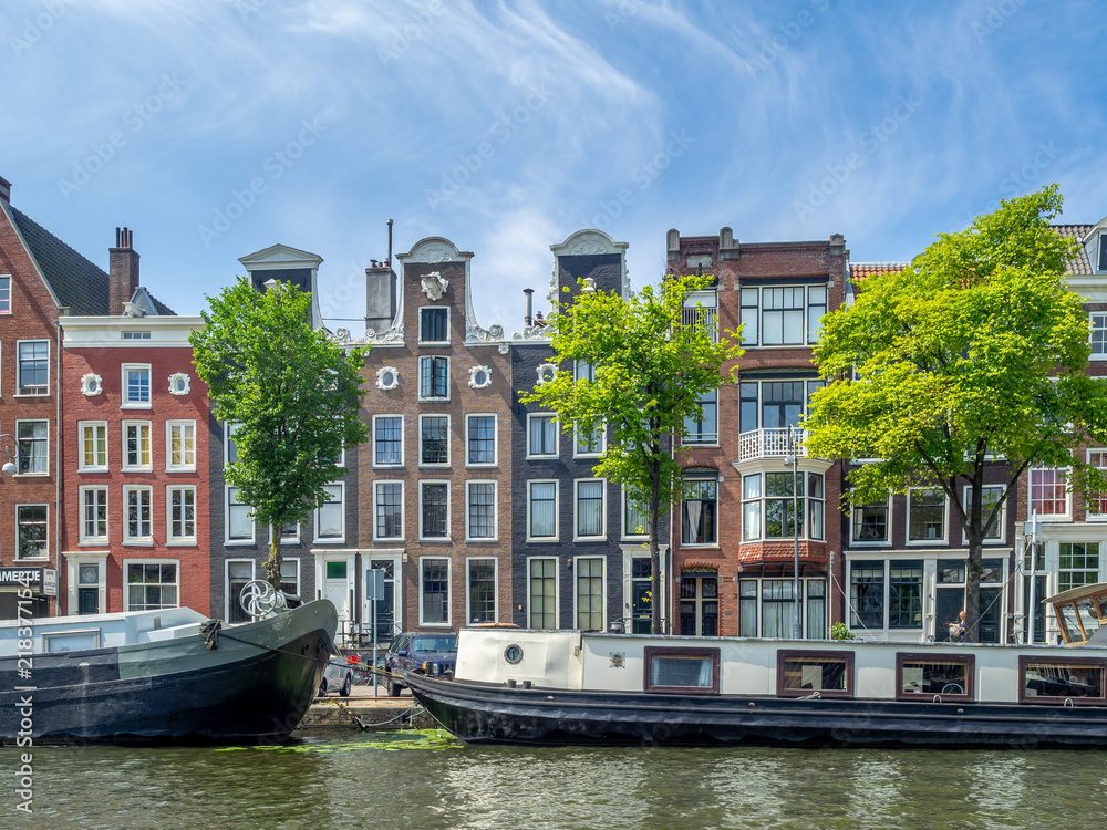 Obraz premium Amsterdam canal, bridge and typical houses, boats and bicycles during the day, Holland, Netherlands.