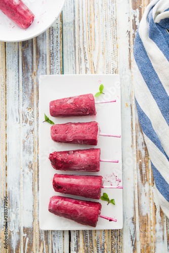 Blackberries popsicle on a white  dish,top view over a blue and gray background photo